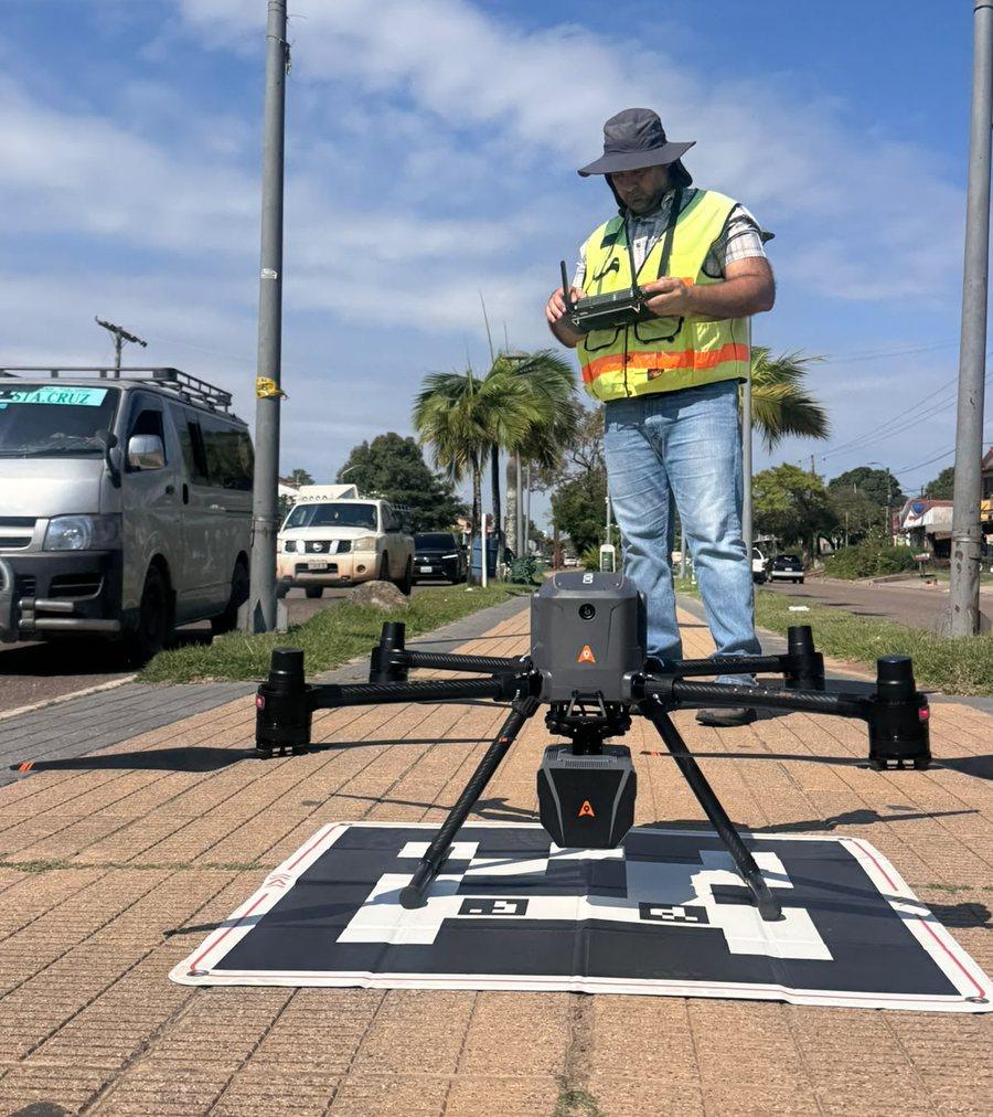 Operador con el radiocontrol junto al dron LiDAR sobre su plataforma de despegue, en una avenida de La Guardia, Santa Cruz
