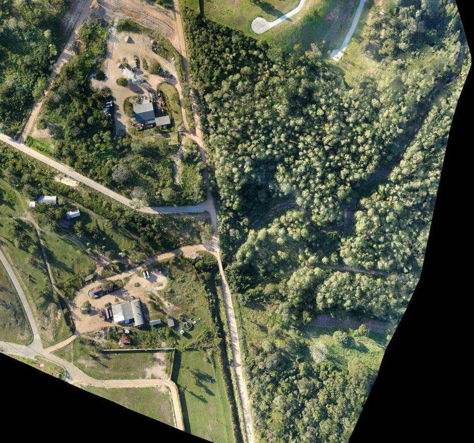 Ortomosaico aéreo georreferenciado de una zona con bosque, caminos de tierra y edificaciones
